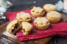 a wooden cutting board topped with mini chocolate chip pies on top of a red cloth