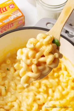 a wooden spoon full of macaroni and cheese on top of a stovetop