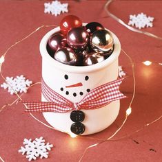 a snowman pot filled with ornaments on top of a table