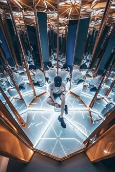 a man is sitting on the floor in front of mirrored walls and mirrors with lights