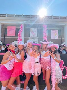 four girls dressed in pink and white posing for the camera with their hands up while wearing matching outfits