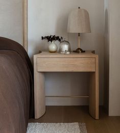 a wooden table with a lamp on it next to a bed