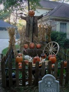 a scarecrow statue surrounded by pumpkins and other decorations in front of a house