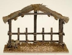 a small wooden structure with hay and straw on the top, in front of a white wall