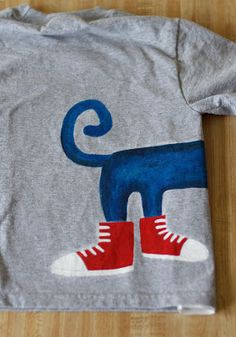 a t - shirt with a cat painted on it's chest and red shoes