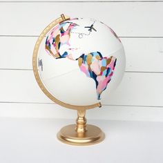 a globe with an airplane painted on the top and bottom, sitting on a stand