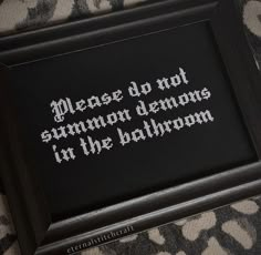 a black framed cross stitch with the words please do not summon demons in the bathroom