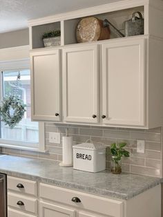 a kitchen with white cabinets and gray counter tops, along with a dishwasher