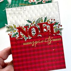 someone holding up a christmas card with the word noel on it