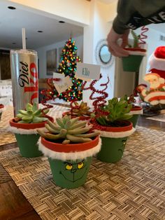 three green cups with plants in them sitting on a table next to a coca - cola can