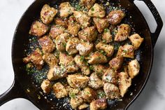 a skillet filled with meat and seasoning on top of a white countertop