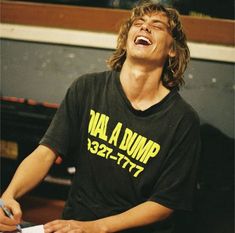 a young man laughing while holding a pen and paper