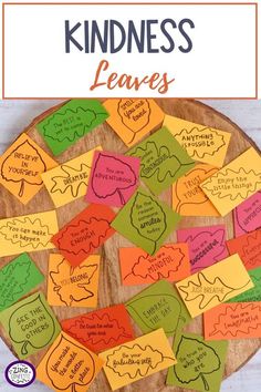 a wooden plate filled with lots of different colored leaves and the words kindness on it