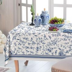 a blue and white table cloth on a dining room table with grapes, grapes in vases