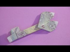 an origami bird made out of money on a pink background