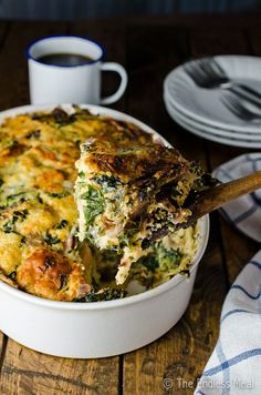 a casserole dish with broccoli, cheese and other toppings on a wooden table