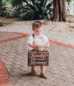 a little boy holding a sign that says daddy are you ready? here comes mommy