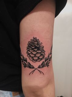 a small pine cone tattoo on the arm