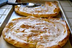 two pizzas sitting on top of a pan covered in white sauce next to a spatula