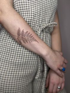 a woman's arm with a fern tattoo on the left side of her body