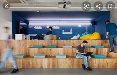 two men are sitting on the stairs in an office with blue walls and wooden steps