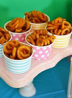 there are many small cups with food in them on the table and one is filled with pretzels