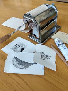 some art supplies are laying out on a wooden table with paper and paintbrushes