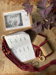 the contents of a knitting kit are laid out on a wooden table next to some purple leaves