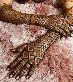 two hands with henna tattoos on them sitting next to each other in front of a pink rug