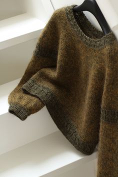 a brown sweater hanging on the side of a window sill