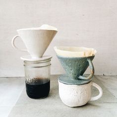 an old fashioned coffee maker next to a glass jar with liquid in it and another item on the ground