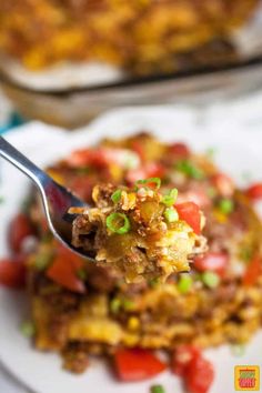 a spoon full of food on top of a plate with another dish in the background