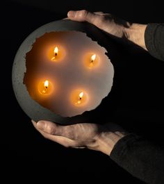 a person holding a bowl with candles in it