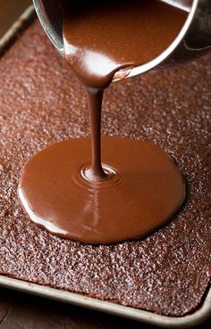 a person pouring chocolate sauce on top of a pan