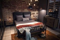 a bedroom with brick walls and flooring is lit up by pendant lights above the bed