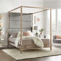 a bedroom with a four poster bed and white rugs on the hardwood flooring