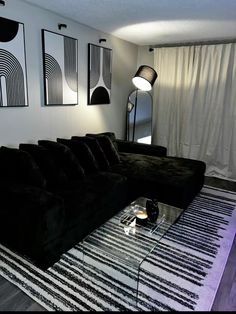 a living room with black couches and white curtains