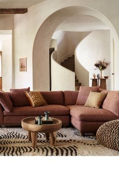 a living room filled with lots of furniture next to a spiral stair case on the wall