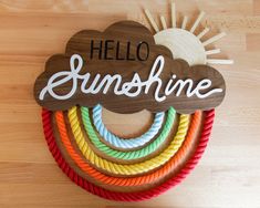 a wooden sign that says hello sunshine on top of some colorful rope and wood rings