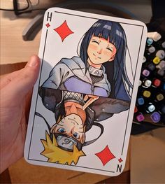 a hand holding up a playing card with an image of a woman on it's face