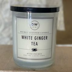 a white ginger tea candle sitting on top of a table