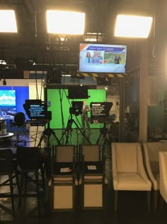 an empty room with chairs and televisions on the wall, in front of green screen