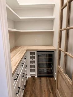 an empty pantry with white cabinets and wood flooring