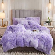 a bed with purple comforters and pillows on it