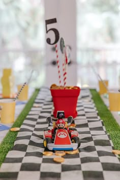 a toy race car on a checkered tablecloth with candy canes in the background