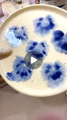 a plate with blue flowers on it being held up by someone's hand in front of them