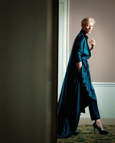 a woman in a blue dress is walking through a doorway