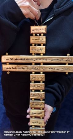 a person is holding a wooden cross with writing on it