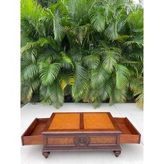 an old wooden box sitting in front of some palm trees and other greenery on the ground