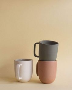 three cups sitting next to each other on top of a beige surface with one cup in the middle